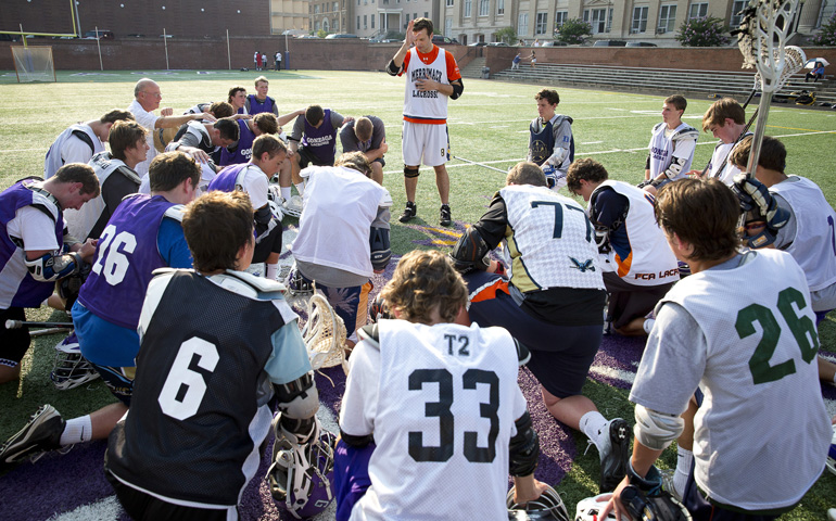 Fr. Mark Ivany gives a blessing over lacrosse players before a summer scrimmage at Gonzaga College High School in Washington in July. (CNS/Tyler Orsburn) 
