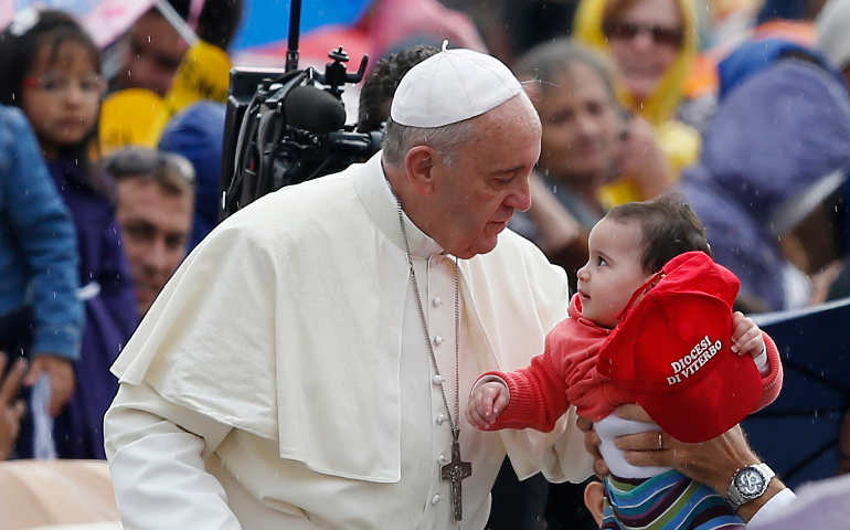 Pope Francis greets a baby as he arrives to lead his general audience in St. Peter's Square at the Vatican Oct. 9. (CNS photo/Paul Haring) 