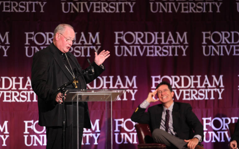 New York Cardinal Timothy Dolan speaks at a Sept. 14 forum at Fordham University while comedian Stephen Colbert laughs in the background. (Fordham University)