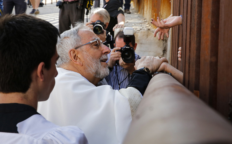 Bishop Gerald Kicanas of Tucson, Ariz., blesses people in Mexico as he distributes Communion through the border fence April 1, 2014, in Nogales, Ariz. (CNS/Nancy Wiechec)