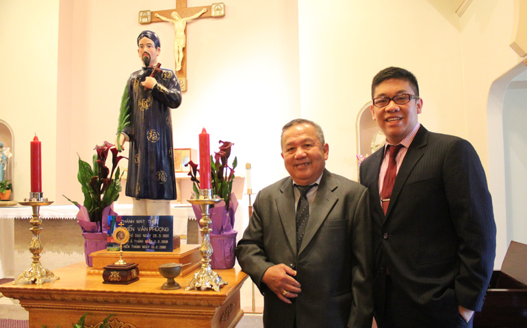 Huynh Thanh Nguyen and Phu Nguyen stand with statue in 2013 of their ancestor, St. Matthew Nguyen Van Phuong, in a chapel at the Southeast Asian Vicariate campus in Portland, Ore. (CNS/Catholic Sentinel/Ed Langlois)