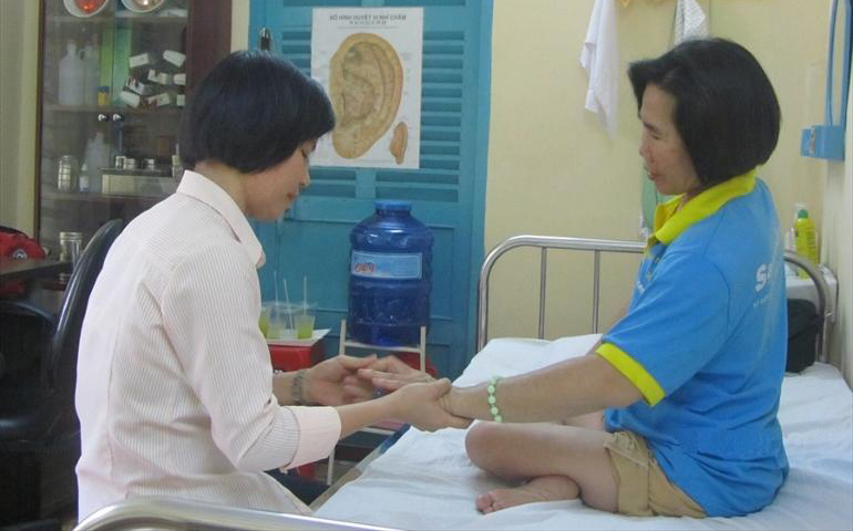 Sr. Anna Nguyen Thi Dung of Our Lady gives physical therapy to Nguyen Thi Mai. (Teresa Hoang Yen)