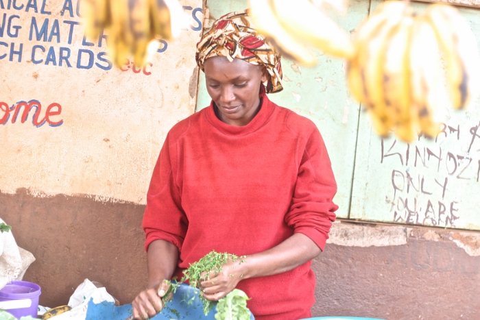 A woman in Nairobi’s Kangemi Slum sells vegetables by a road side that is being constructed to allow Pope Francis access to the slum during his visit to the poor in Kenya. (GSR photo/Lilian Muendo)
