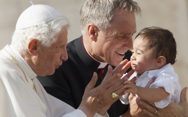 Pope Benedict XVI greets a child as he leaves his general audience Wednesday in St. Peter's Square at the Vatican. Also pictured is Msgr. Georg Ganswein, the pope's personal secretary. (CNS/Paul Haring) 