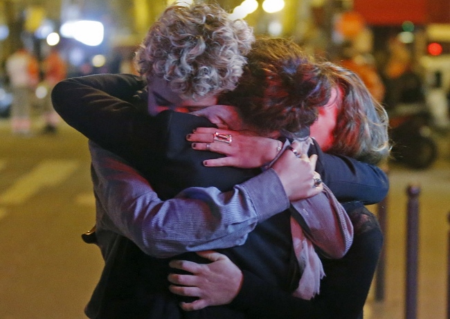People hug on the street near the Bataclan concert hall following fatal attacks in Paris, France, Nov. 14, 2015. Gunmen and bombers attacked busy restaurants, bars and a concert hall at locations around Paris on Friday evening, killing dozens of people in what a shaken French president described as an unprecedented terrorist attack. (Courtesy of REUTERS/Christian Hartmann)