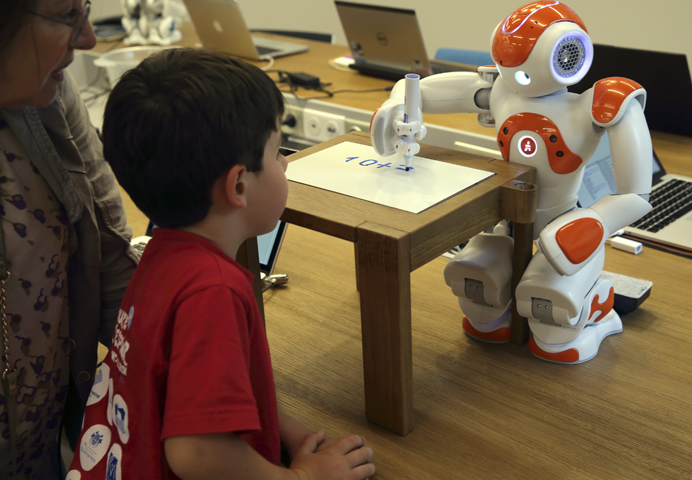 A child watches a humanoid robot, Nao, doing math July 2, 2014, at a Aldebaran Robotics workshop during its opening week in Issy-les-Moulineaux near Paris. (CNS/Reuters/Philippe Wojazer)
