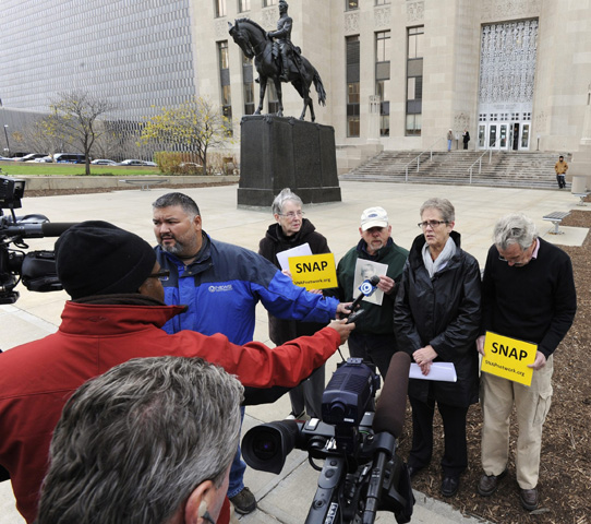 Television reporters speak to members of Survivors Network of those Abused by Priests as they stand in front of the Jackson County, Mo., Courthouse in November 2011 to announce a lawsuit against the diocese of Kansas City-St. Joseph, Mo., over failing to report a priest suspected of child abuse. (CNS/Reuters/Dave Kaup)