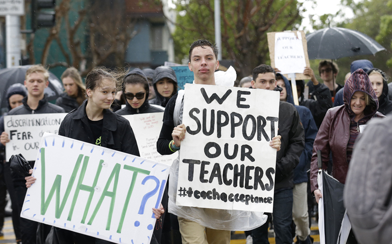 Students and supporters carry signs Friday as they walk toward Sacred Heart Cathedral Preparatory after a vigil outside of St. Mary's Cathedral in San Francisco. (AP Photo/Jeff Chiu)