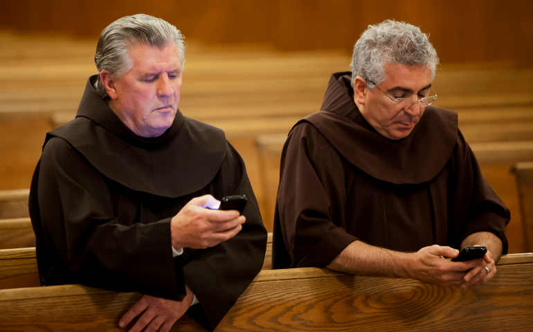 Texting in church!? Franciscan Brothers Richard Mcfeely and Robert Frazzetta read prayer requests on their mobile phones Jan. 3 at St. Anthony Friary in Butler, N.J. The largest group of Franciscan friars in the United States is offering the faithful a new way to pray in th e digital age by accepting prayer requests via text messages. (CNS photo/Octavio Duran)