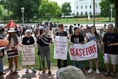 Protesters hold signs with White House in background
