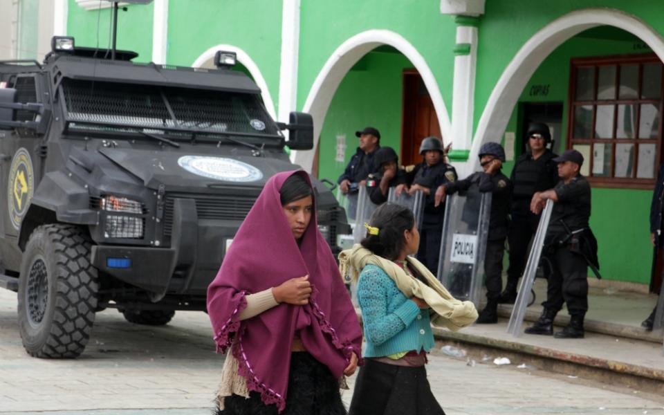 Indigenous women pass riot police standing guard on the city square of San Juan Chamula, Mexico, in late July. (CNS/EPA/Rene Arauxo) 