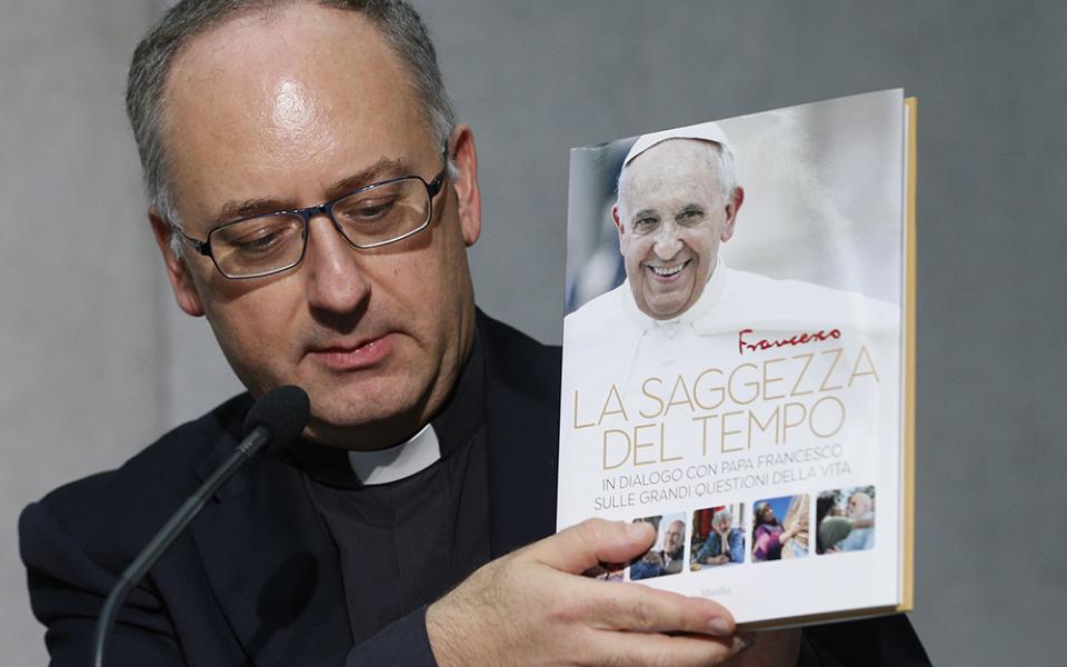 Jesuit Fr. Antonio Spadaro holds a copy of the book "Sharing the Wisdom of Time" during a briefing Oct. 23, 2018, at the Vatican. (CNS/Paul Haring)