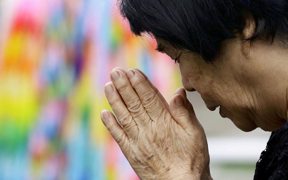 A woman prays for victims of the 1945 atomic bombing at Nagasaki's Atomic Bomb Hypocenter Park in Japan Aug. 9, 2020, the 75th anniversary of the bombing. Former priest Robert Cushing is in Japan leading a reconciliation pilgrimage for the bombings with 10 others, most of them members of Pax Christi USA. (CNS/Reuters/Kyodo)