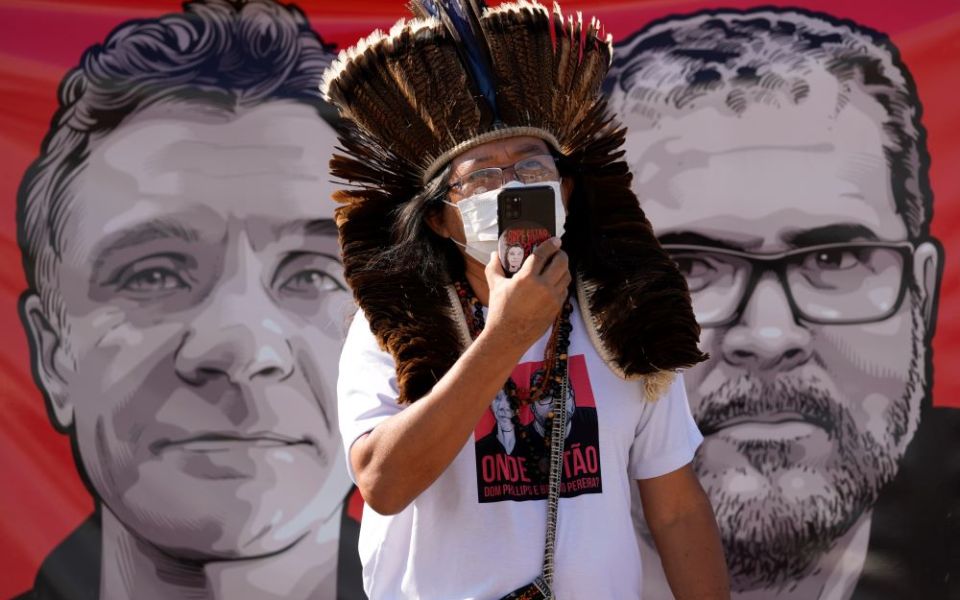 Indigenous leader Kamuu Wapichana stands in front of a banner that show images of missing freelance British journalist Dom Phillips, left, and Indigenous expert Bruno Pereira, during a protest.