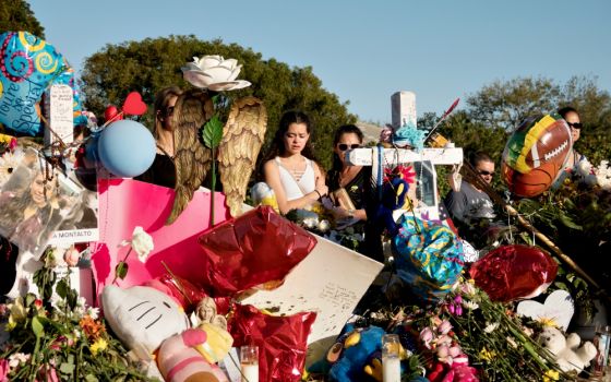 A young woman mourns in front of a memorial to mass shooting victims Feb. 25 at Marjory Stoneman Douglas High School in Parkland, Florida. (CNS/Reuters/Angel Valentin)