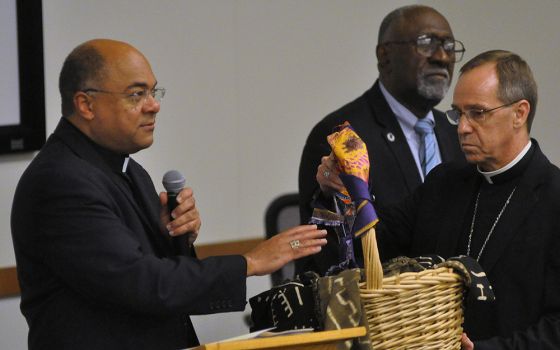 During a 2019 listening session on racism in Indianapolis, Bishop Shelton Fabre of Houma-Thibodaux, Louisiana, blesses a basket (held by Indianapolis Archbishop Charles Thompson) containing people's written accounts of experiences of racism. (CNS)