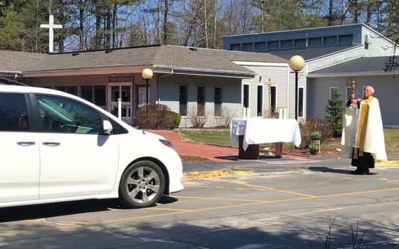 Fr. Lou Phillips, pastor of Our Lady of Perpetual Help Parish in Windham, Maine, holds the Blessed Sacrament April 19 during a "drive-thru" Divine Mercy Sunday blessing in the church parking lot, amid the coronavirus pandemic. (CNS)