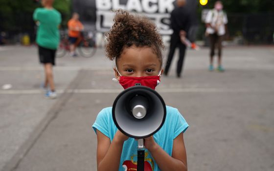Mischa, 6, from Maryland, holds a bullhorn in front of a "Black Lives Matter" protest sign near the White House in Washington June 10, 2020. (CNS/Reuters/Kevin Lamarque)
