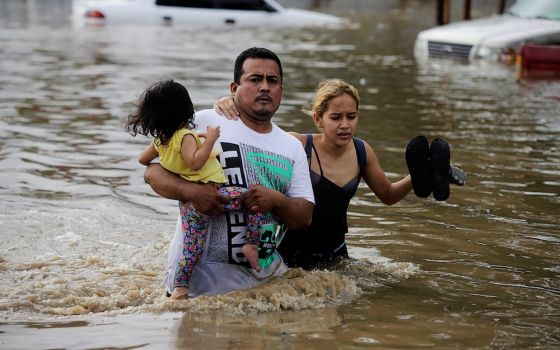 People wade through floodwaters in La Lima, Honduras, in November 2020, in the wake of Hurricane Eta. (CNS photo/Jorge Cabrera, Reuters)