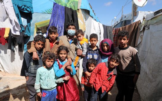 Syrian refugee Abd al-Razzak Dasher stands with his children at an informal tent settlement in the Bekaa Valley in Lebanon March 12, 2021. As Syria marks 10 years of devastating conflict, the country is in economic and social shambles with millions of peo