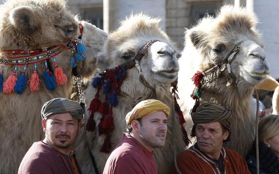 Three camels stand behind men in traditional attire in St. Peter's Square as Pope Francis leads the Angelus on the feast of the Epiphany in 2018 at the Vatican. (CNS/Paul Haring)