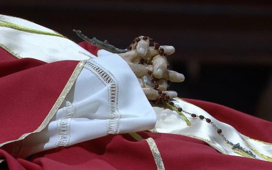 Pope Benedict XVI's folded hands have a ring on one finger and hold a rosary