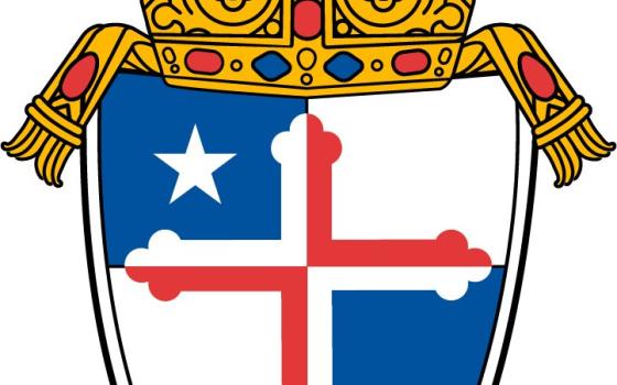 A crown sits on top of a shield with a white and red cross with blue patches in diagonal corners