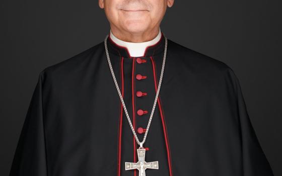 An older white man wears glasses, a bishop's cassock and a pectoral cross