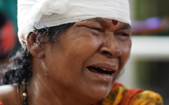 A woman wearing a bindi with a bandage wrapped around her head sobs