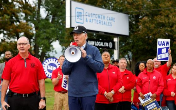 U.S. President Joe Biden speaks next to Shawn Fain, president of the United Auto Workers, as he joins striking UAW members on the picket line outside the GM's Willow Run Distribution Center in Belleville, Michigan, Sept. 26. Biden became the first known sitting U.S. president to join a labor strike. (OSV News/Reuters/Evelyn Hockstein)