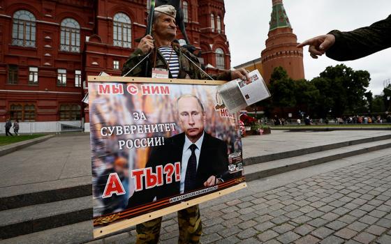 A man holds a placard in support of Russian President Vladimir Putin as a tower of the Kremlin is seen in the background in Moscow June 24. (OSV News/Reuters/Maxim Shemetov)