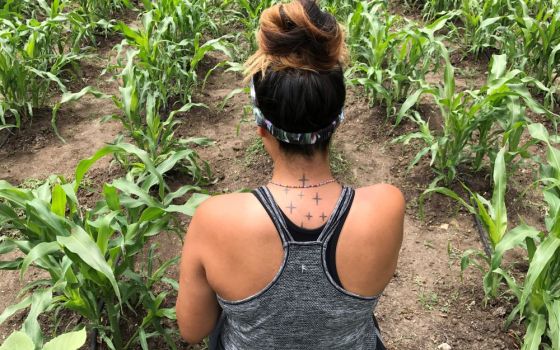 Mee-Kai Spottedhorsechief, a Pawnee, is in a garden of white flour corn in Nebraska. On the back of her neck is a tattoo of Pawnee four-pointed stars. (Ronnie O’Brien)