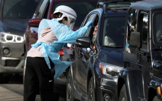 A health care worker in Denver tests people for the coronavirus at a drive-thru testing station March 11, 2020. (CNS/Reuters/Jim Urquhart)