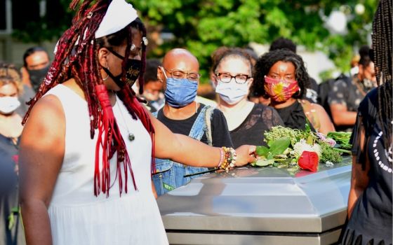 Dannielle Brown places flowers on an empty casket during her "living funeral" in Pittsburgh on Aug. 6, more than a month into her hunger strike. Brown told NCR on Aug. 31 that she is not sure she will survive her strike, and that she wants to be remembere
