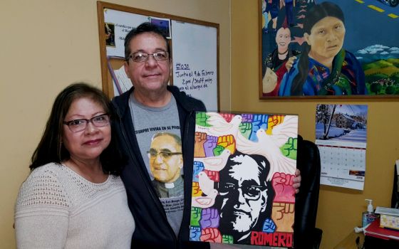 Many images of Blessed Archbishop Óscar Romero adorn the office of Tony Arteaga, shown here with his wife, Delmy, at Los Angeles’ Dolores Mission Parish. (NCR photo/Dan Morris-Young)