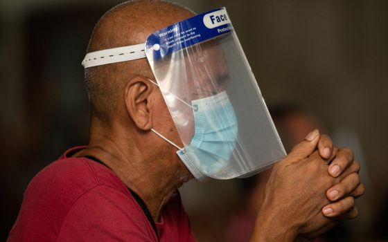 A man wearing a protective mask and face shield prays inside the Minor Basilica of the Black Nazarene in Manila, Philippines, Oct. 2, 2020, during the COVID-19 pandemic. (CNS/Reuters/Eloisa Lopez)