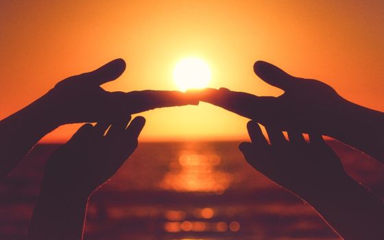 Hands touching, background of sunset (Unsplash/Alonso Reyes)