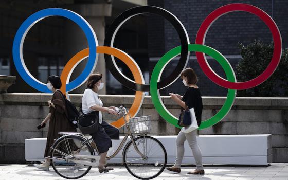 People walk by the Olympic rings installed by the Nippon Bashi bridge in Tokyo on Thursday, July 15, 2021. (AP Photo/Hiro Komae)