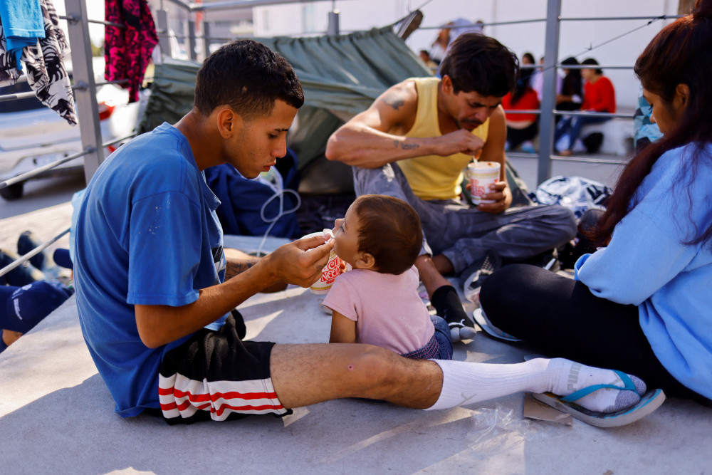 Venezuelan migrants, expelled from the U.S., eat at the U.S.-Mexico border in Ciudad Juarez, Mexico, Oct. 16, 2022. They were sent back to Mexico under Title 42 as part of a new policy to curb the number of illegal crossings. (CNS photo/Jose Luis Gonzalez, Reuters)