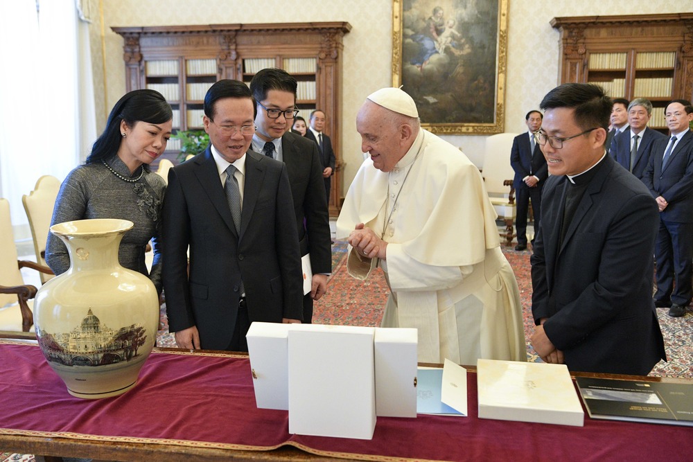 Pope, President, and First Lady stand in front of table bearing mutual gifts. 
