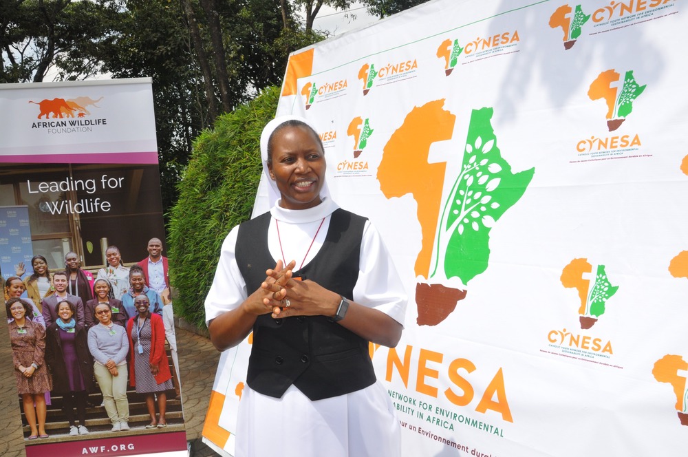 Sister stands with hands folded in front of organization banner