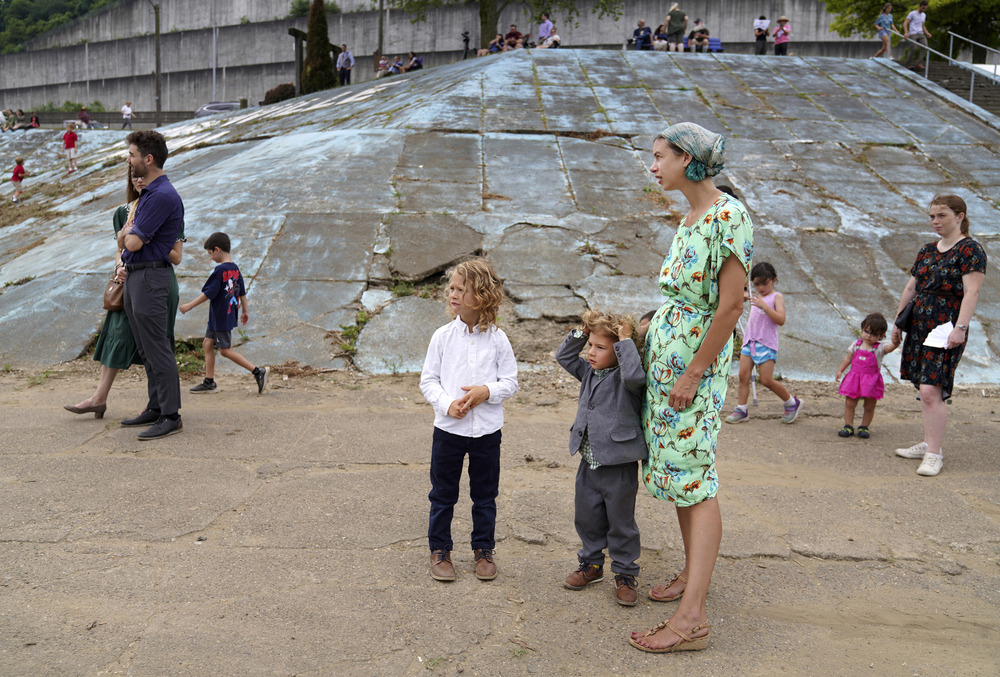 Woman stands with two children, as others walk in background