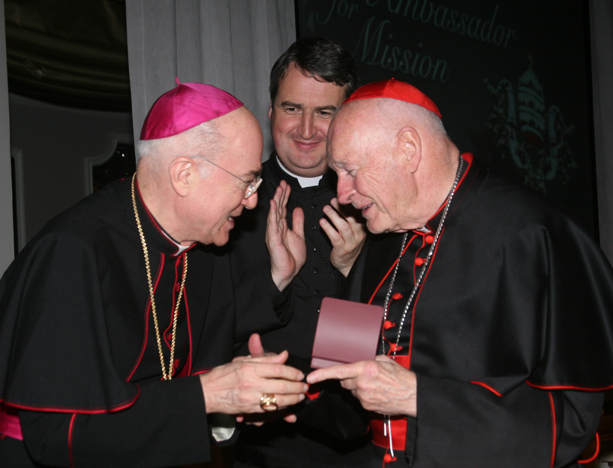 Archbishop Carlo Maria Vigano, then nuncio to the United States, congratulates then-Cardinal Theodore McCarrick of Washington at a gala dinner sponsored by the Pontifical Missions Societies in New York in May 2012. The archbishop has since said Cardinal McCarrick already was under sanctions at that time, including being banned from traveling and giving lectures. Oblate Fr. Andrew Small, center, director of the societies, said Vigano never tried to dissuade him from honoring the cardinal at the gala. (CNS/PM