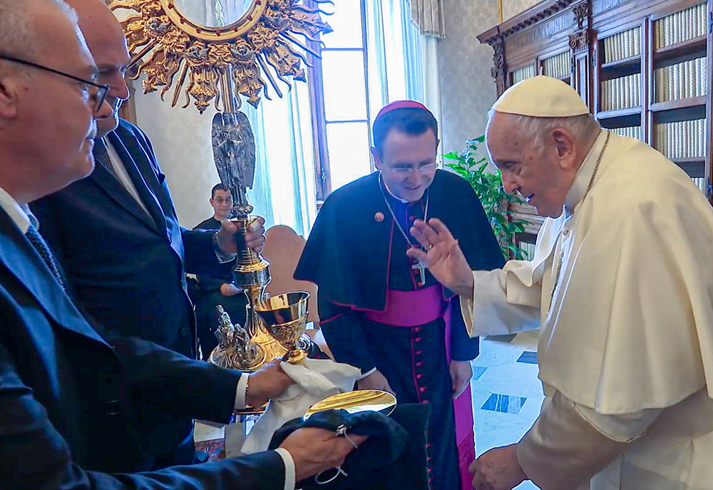 Pope Francis blesses a 4-foot-tall monstrance, a chalice and a paten as Bishop Andrew Cozzens of Crookston, Minnesota, looks on during an audience in the library of the Apostolic Palace June 19, 2023. The blessing took place during the pope's meeting with members of the organizing committees of the U.S. National Eucharistic Congress and Eucharistic Revival. (CNS screenshot/Vatican Media)