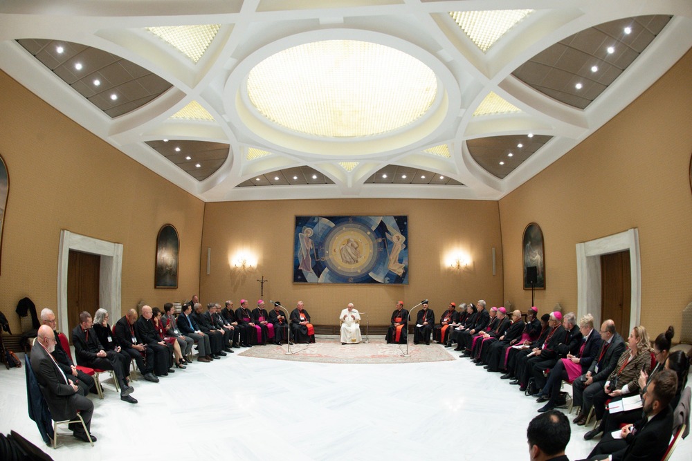 Pope Francis sits in middle of large u-shaped assembly. 