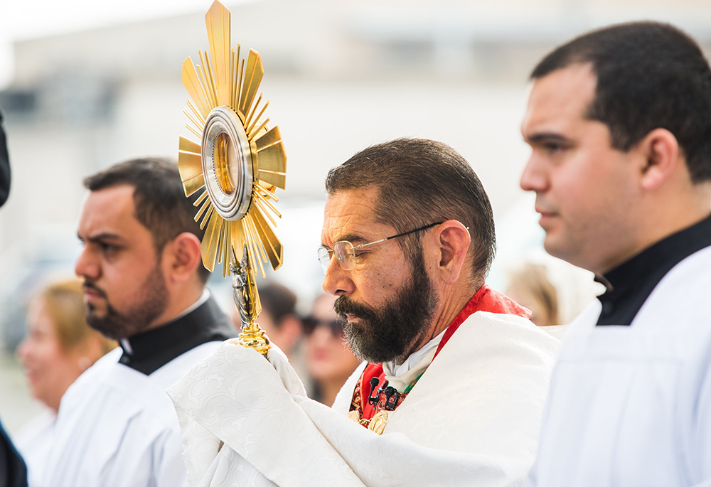 Bishop Daniel Flores carries the monstrance as pilgrims process through the streets of Brownsville, Texas, May 19 from the Cathedral of the Immaculate Conception to Sacred Heart Mission. The procession kicked off the St. Juan Diego Route of the National Eucharistic Pilgrimage. (OSV News/Tom McCarthy)