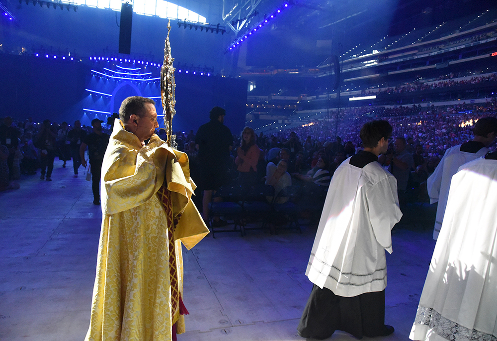 Bishop Andrew Cozzens of Crookston, Minnesota, chairman of the board of the National Eucharistic Congress, Inc., carries the monstrance in a procession during Eucharistic adoration at the opening revival night, July 17, of the 10th National Eucharistic Congress at Lucas Oil Stadium in Indianapolis. (OSV News/The Criterion/Sean Gallagher)