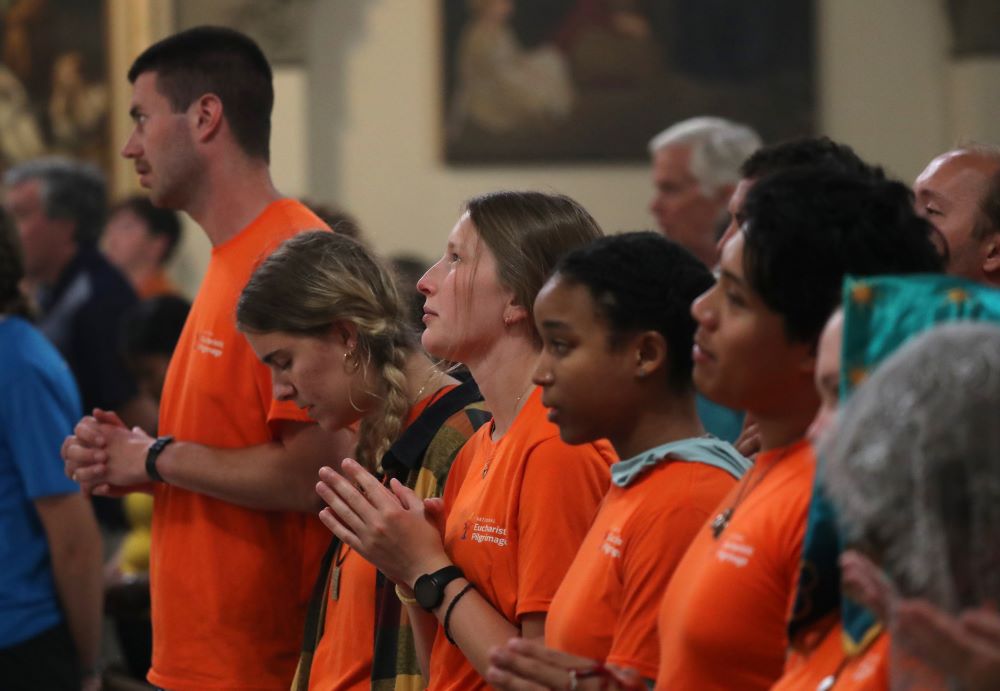 Shayla Elm, a perpetual pilgrim with the Juan Diego Route (center looking up), prays alongside others from her group while attending a Mass to welcome pilgrims at St. John the Evangelist Church in Indianapolis July 16.