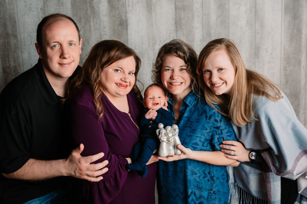 Phil and Meghan Young hold their son Henry with their surrogate mother Rachelle Simon, and her wife Ariell Watson Simon, in April 2021. 