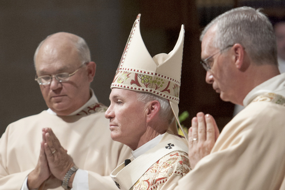 Archbishop Lucas, vested, says Mass. Pictured in profile. 